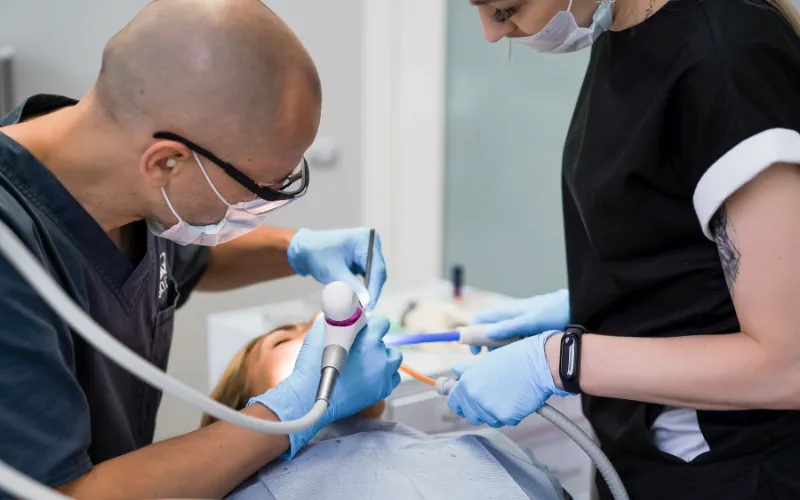 Dentist performing dental implant procedure on patient in modern dental clinic